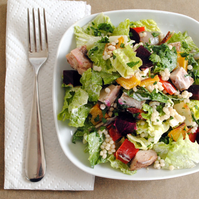 A fresh salad full of roasted vegetables, chicken and Israeli couscous, topped with a tangy Greek yogurt-lemon dressing.