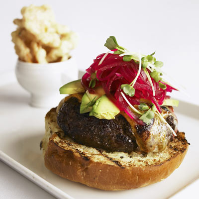 Special burger with avocado and beetroot, a very large burger with special cheese melted on a grill.