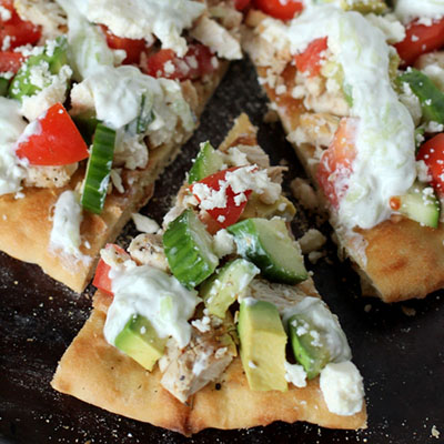 Fresh homemade greek pizza with greek yogurt, garlic, chicken, cucumber, avocado and feta cheese.