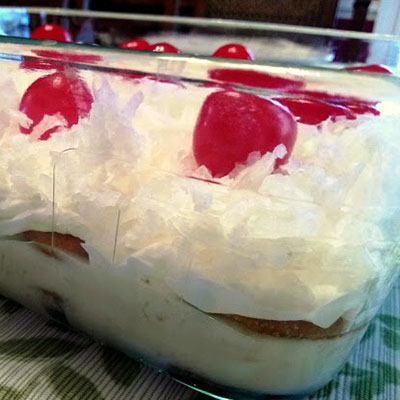 Italian Bakeless Cake: a layered dessert with sweetened condensed milk, lemon juice, pineapple, vanilla wafers, cool whip, coconut and cherries.