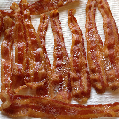 Bakin Bacon Recipe: Make perfect oven baked bacon every time. Place bacon on a sheet pan lined with tin foil up the sides and place pan in a cold oven. Turn oven to 400 degrees. Cook bacon 20-25 minutes. Flip pieces of bacon over 3/4 way through cooking. Drain on paper towels. Ball up the tin foil and toss it. Done! 